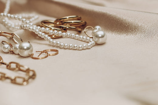 Pearl necklace, gold-plated hoops and pearl earrings on draped cream silk