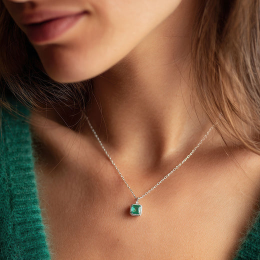 Square green-stone pendant on a silver-tone chain worn with a green knitted jumper