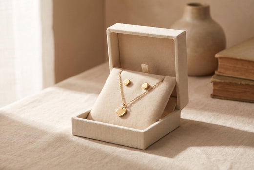 Gold-plated pendant and earrings in an open gift box beside old books