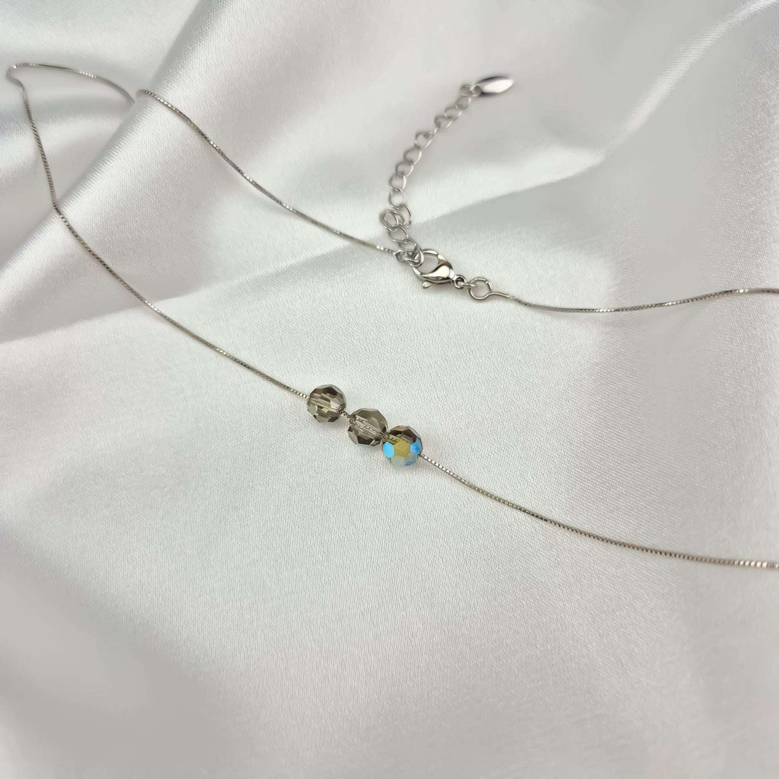 Venetian chain necklace with three crystals and an adjustable chain on white satin