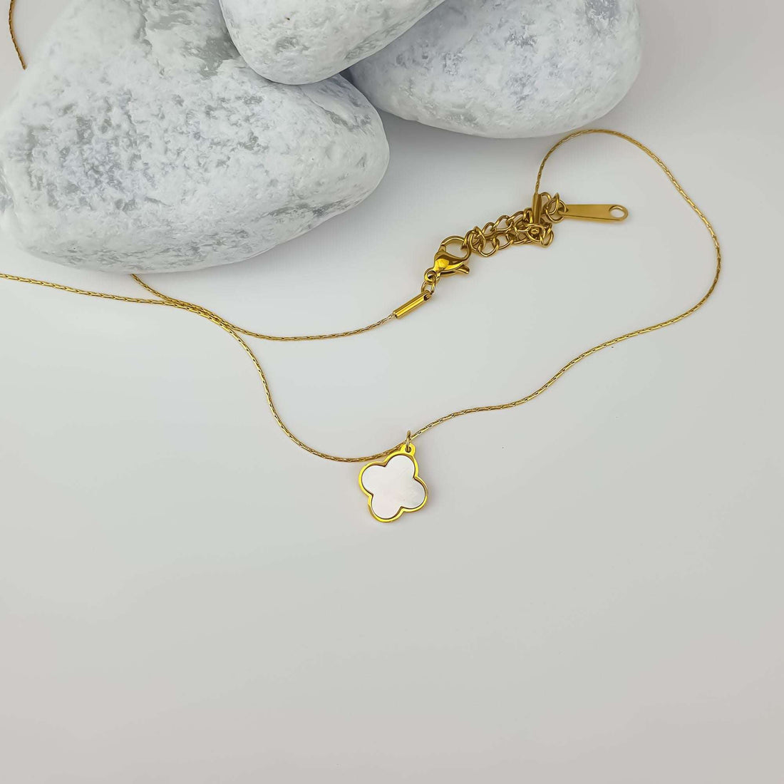 Four-leaf clover necklace on a light surface, clasp and extension chain visible