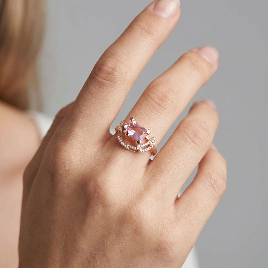 Gold-plated ring with a pink stone and star details on a model's finger
