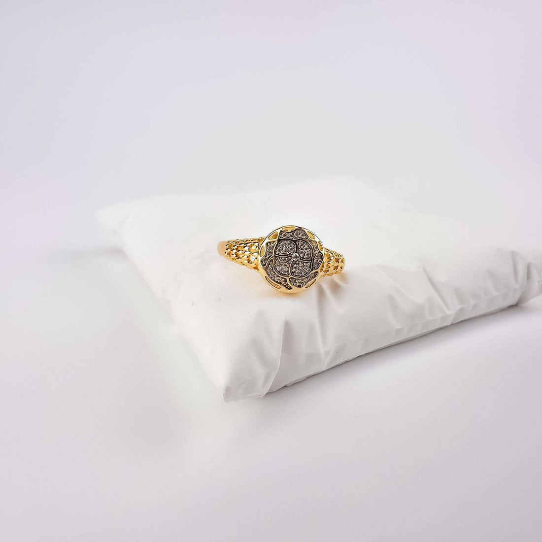 Lace openwork ring with cubic zirconia on a white cushion, warm gold tone