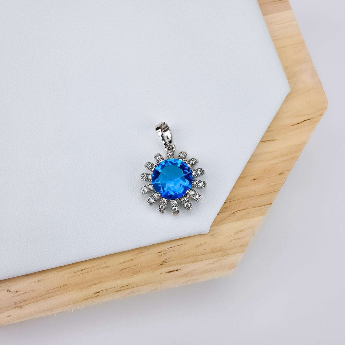 Silver-tone pendant with a round blue stone in a cubic zirconia ray frame