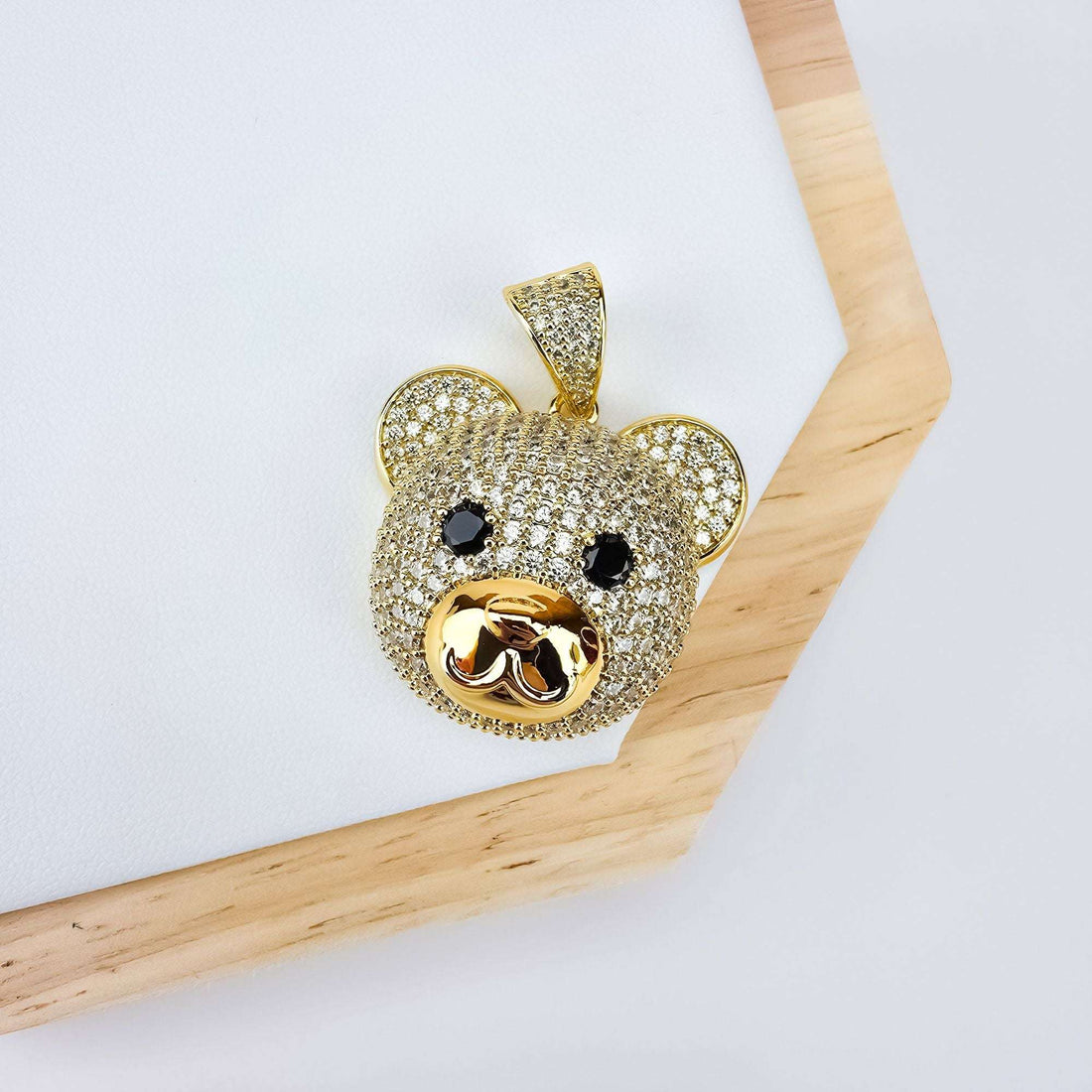 Sparkling teddy bear pendant with a polished snout, angled on a wooden frame