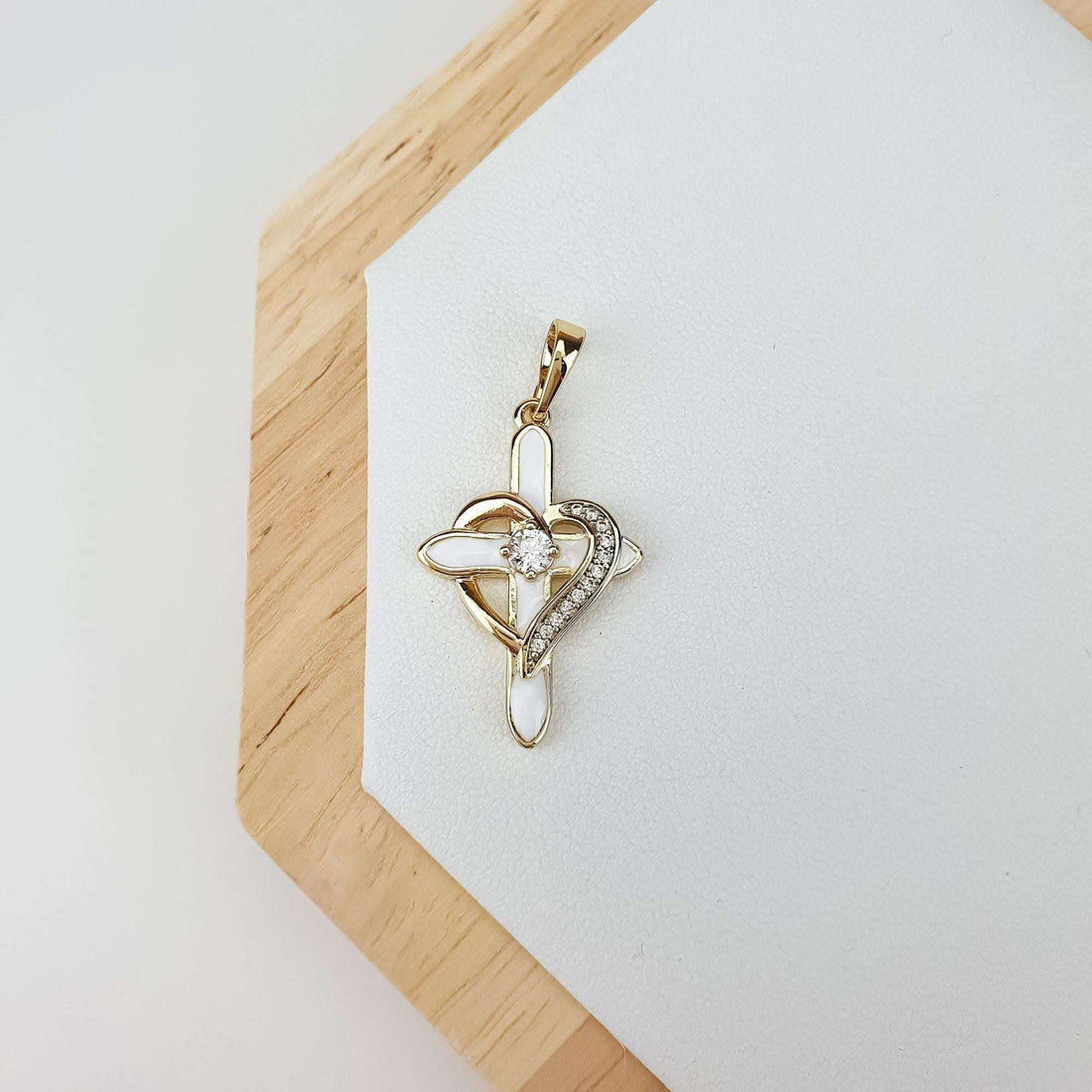 Gold-tone cross and heart pendant in white enamel on a wooden stand