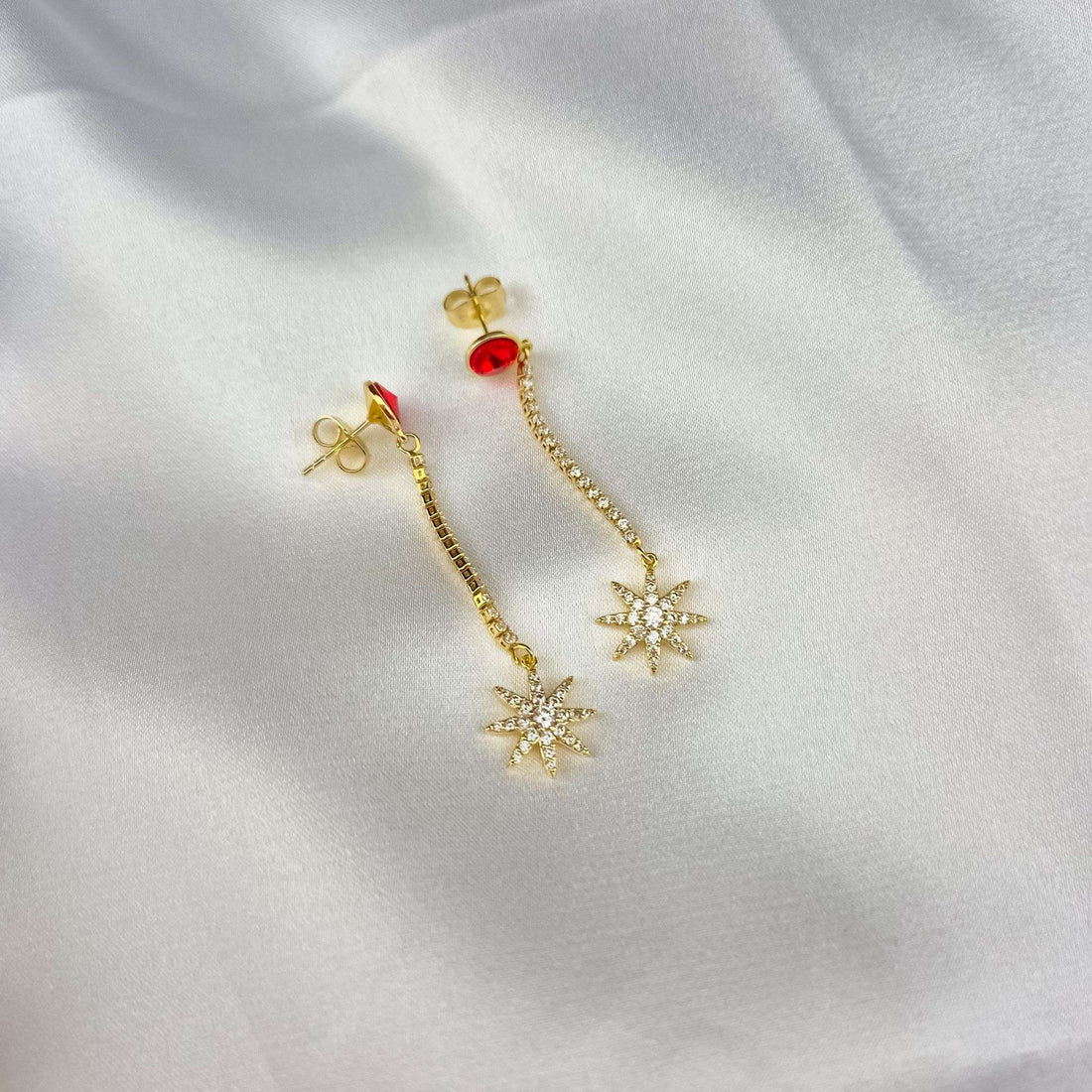 Pair of star earrings on white silk showing push-back posts and cubic zirconia chain