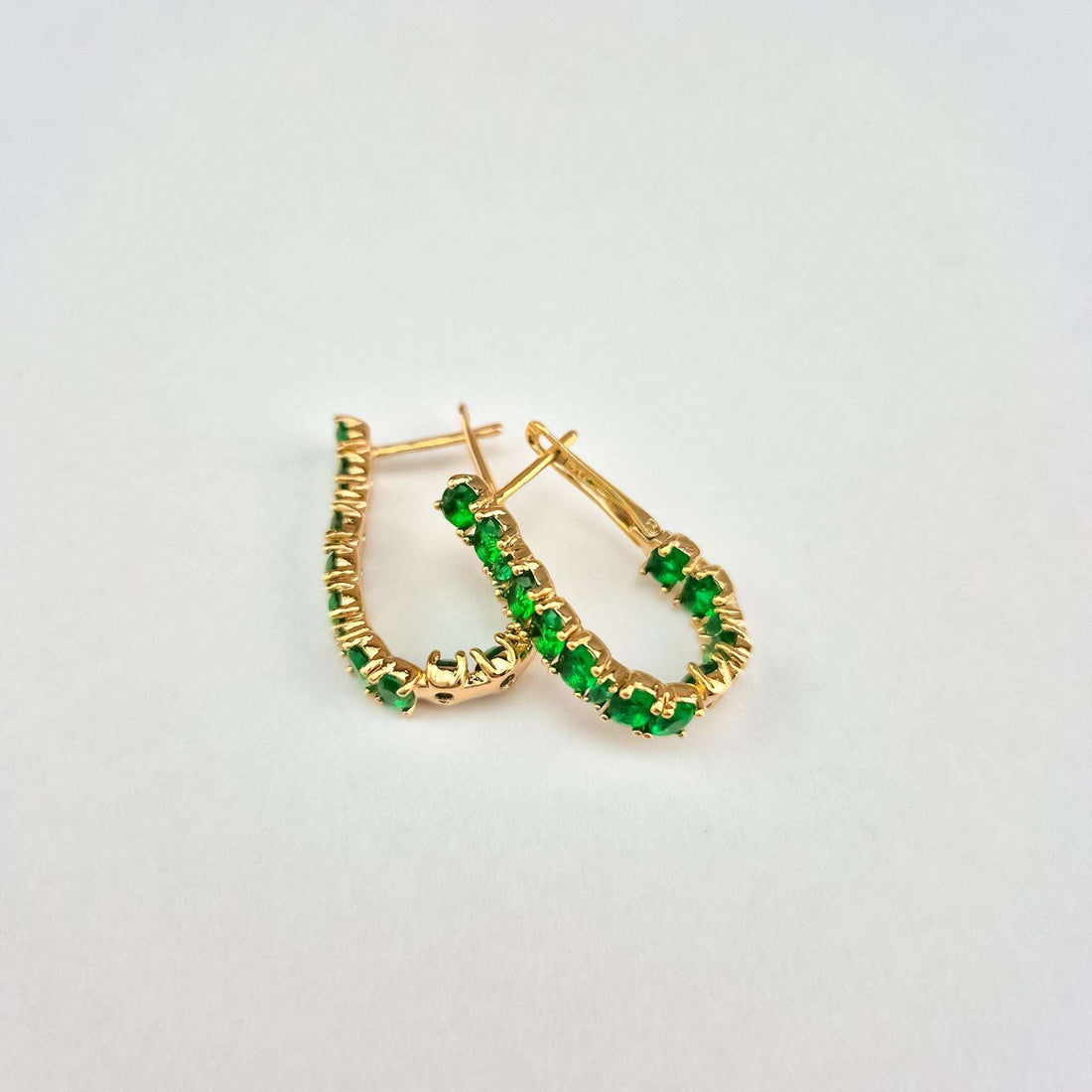 Gold-tone U-shaped earrings with green stones, close-up of the leverback clasp