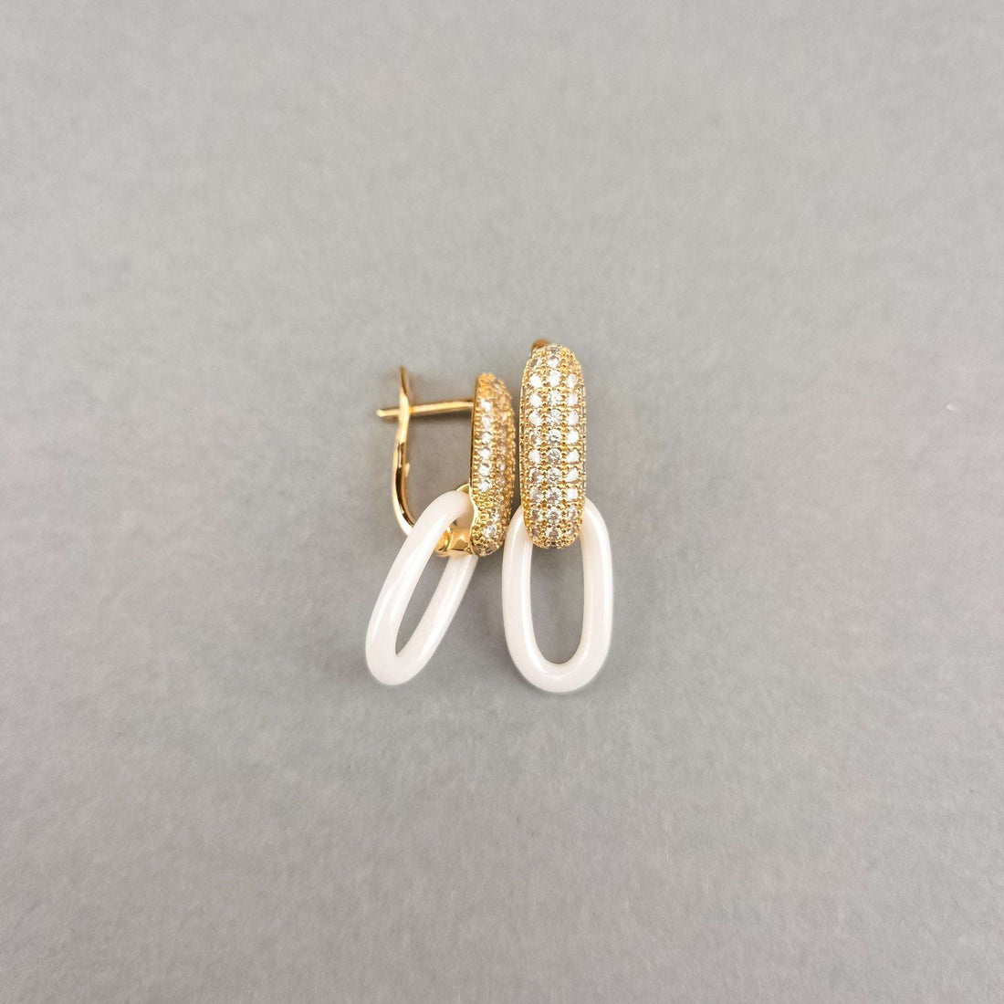 Side view of gold-plated white ceramic earrings with an open leverback clasp