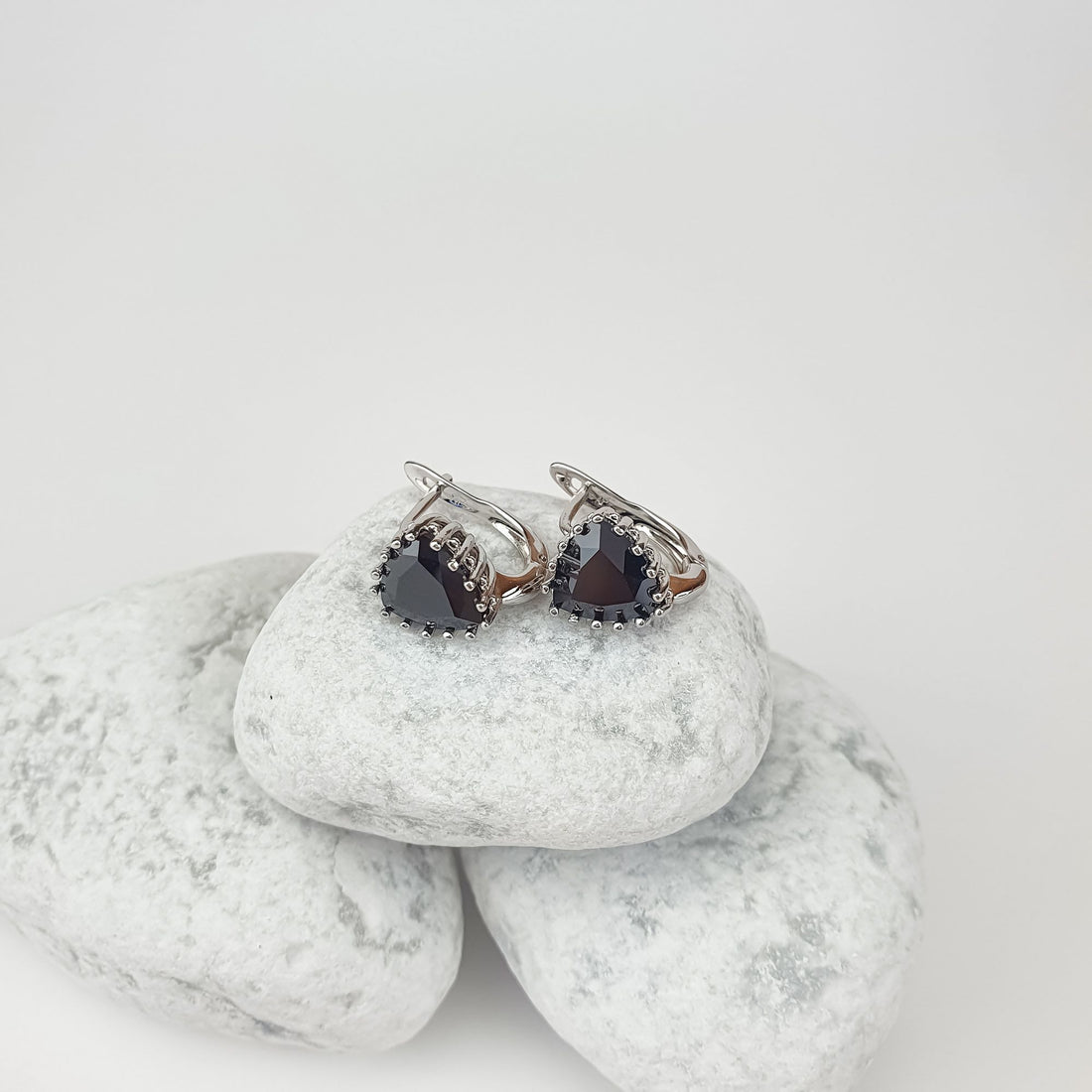 Faceted black triangle stone earrings in a silver-tone setting on white pebbles