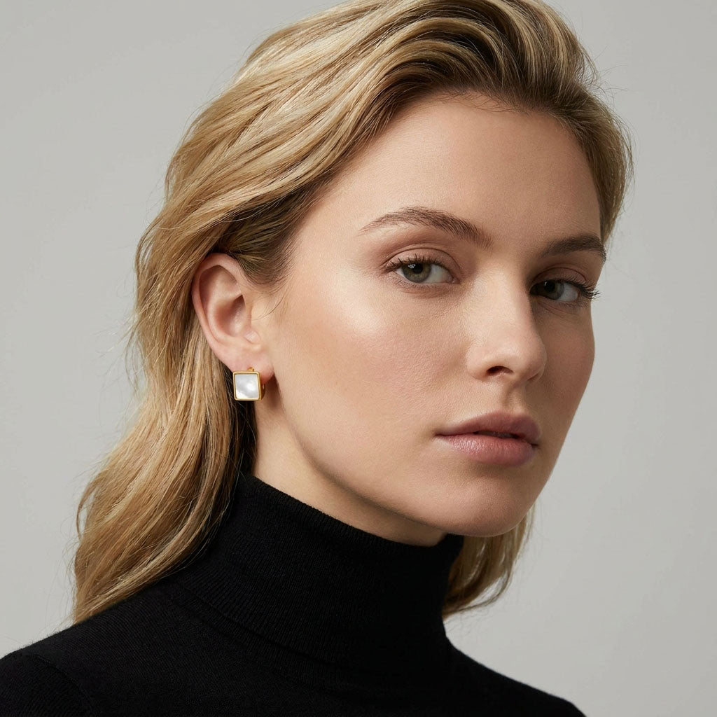 Square pearlescent earring on a model's ear, gold-tone frame with soft sheen