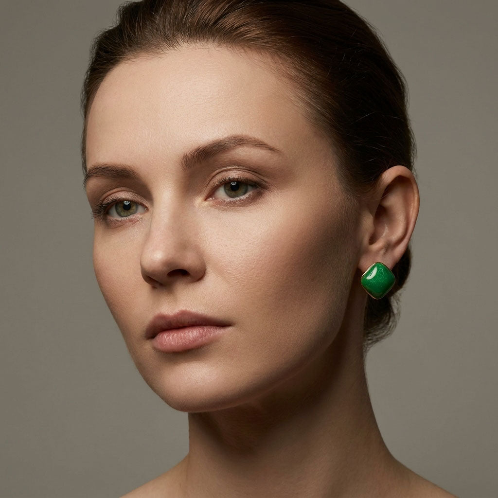 Model on a grey background wearing a green rhombus earring with a gold-tone rim