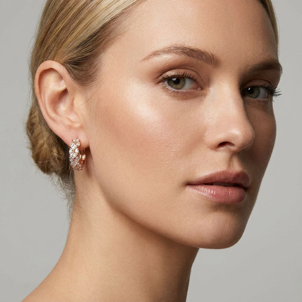 Gold-plated hoop earring with clear crystals on a model's ear, close-up