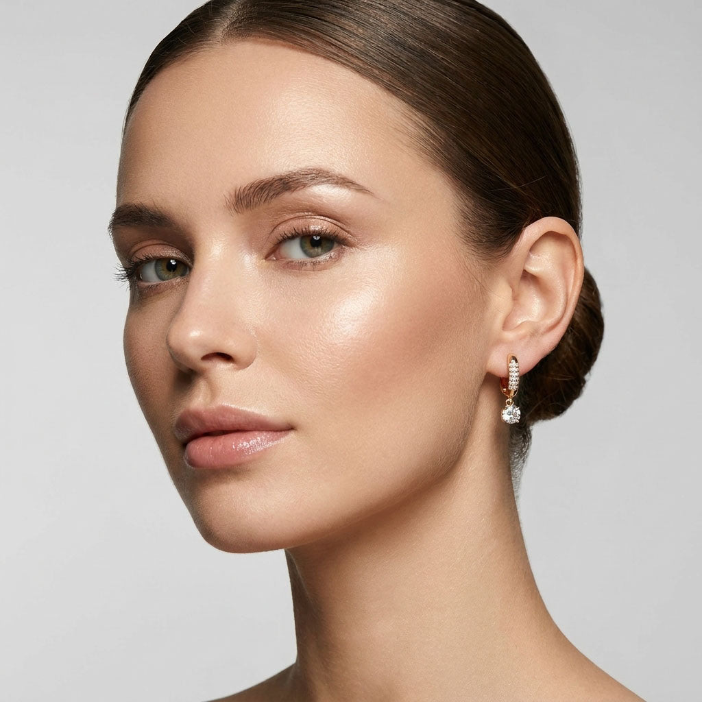 Model wearing gold-plated earrings with a sparkling cubic zirconia drop, side view