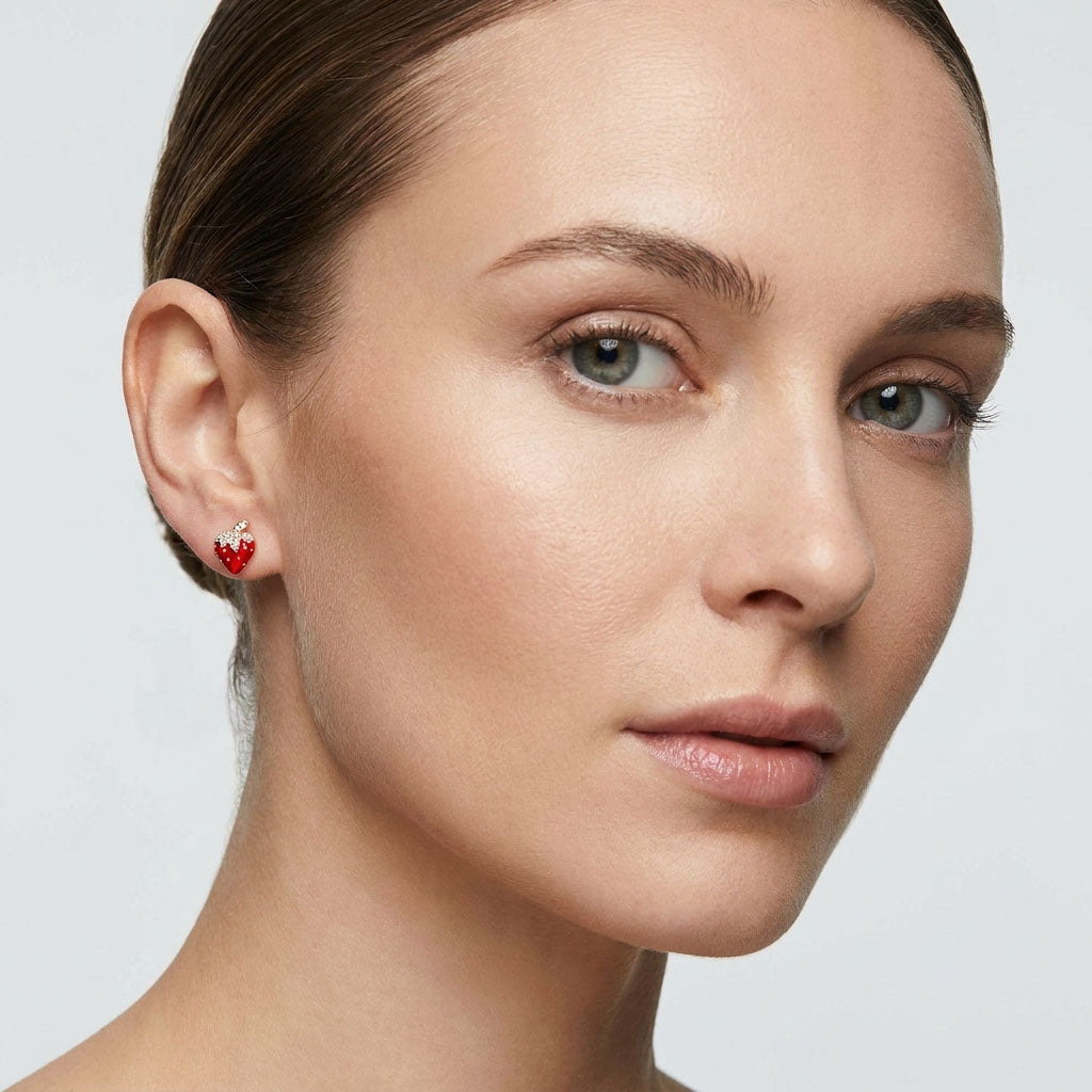 Gold-plated strawberry stud with red enamel and sparkling stones on a model's ear