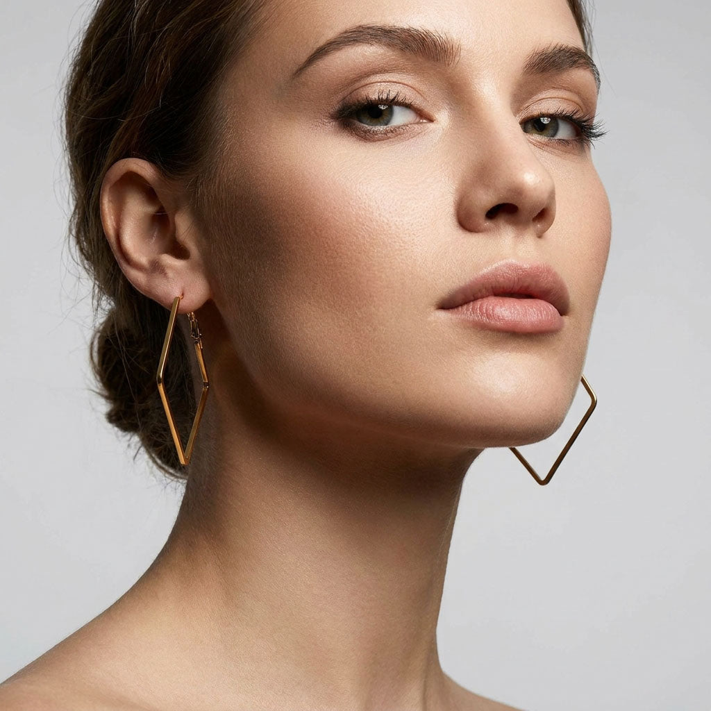 Model wearing large gold-plated rhombus hoops that accent the neckline