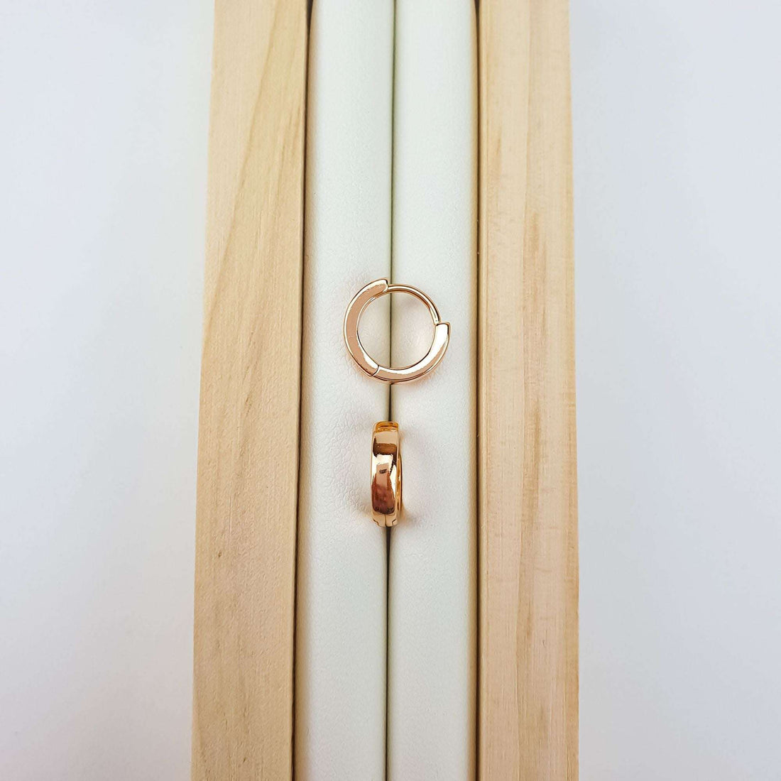 Mini 10 mm rose gold-tone hoop on wood, smooth polished surface