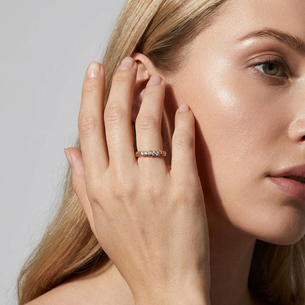 Model wearing a gold-tone cubic zirconia ring, hand raised to her face