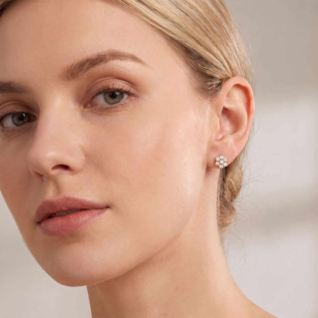 Woman wearing a small flower stud earring with white stones