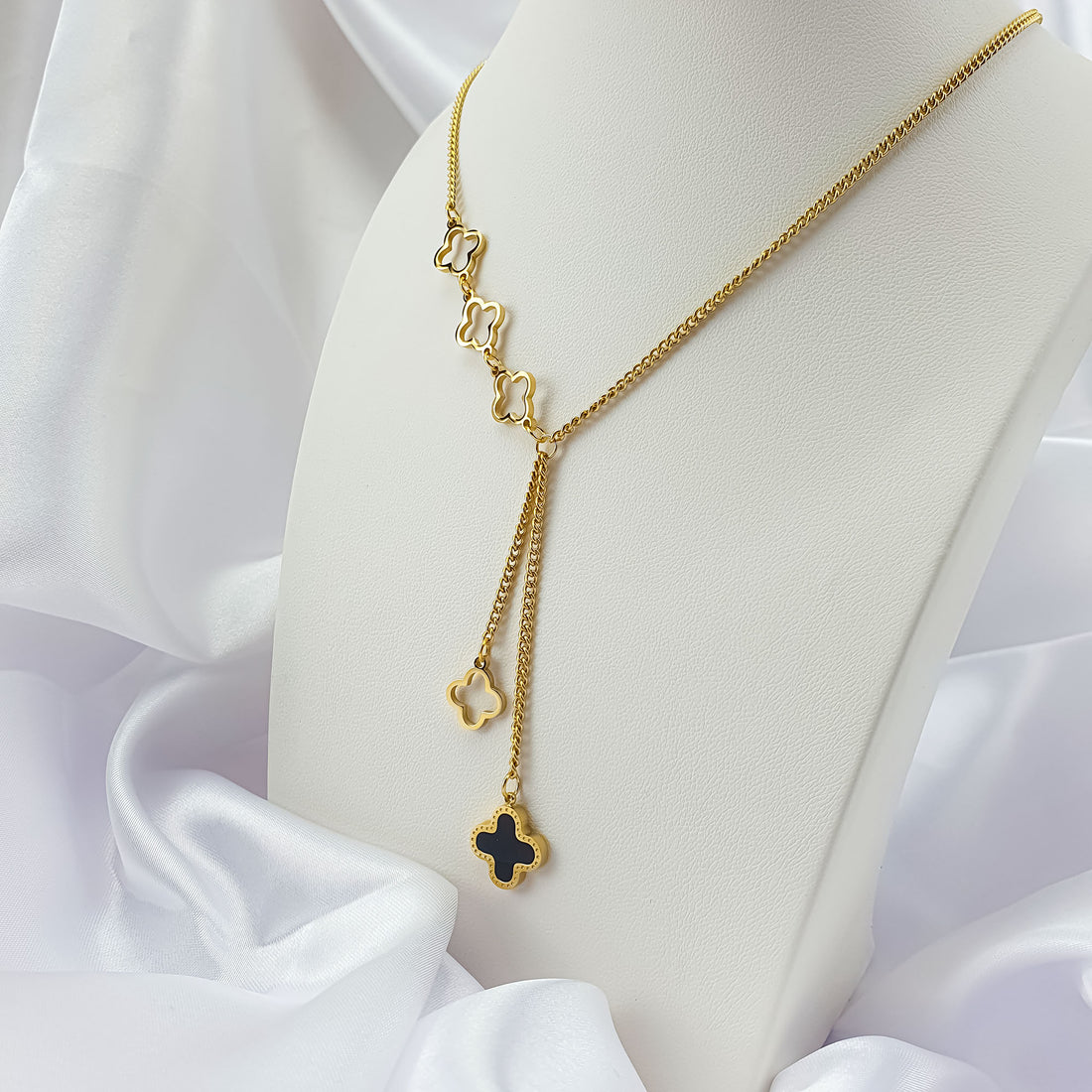 Clover necklace with a black enamel pendant on a stand, textured link chain