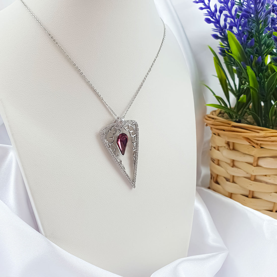 Violet-red stone pendant with a cubic zirconia rim on a white mannequin