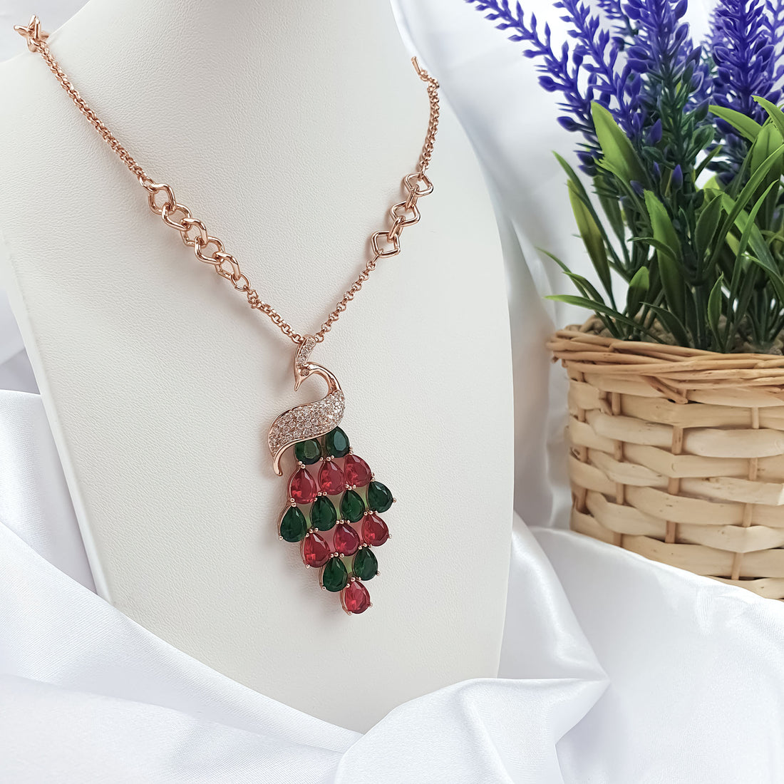 Peacock necklace on a white stand showing the geometric chain and coloured stones