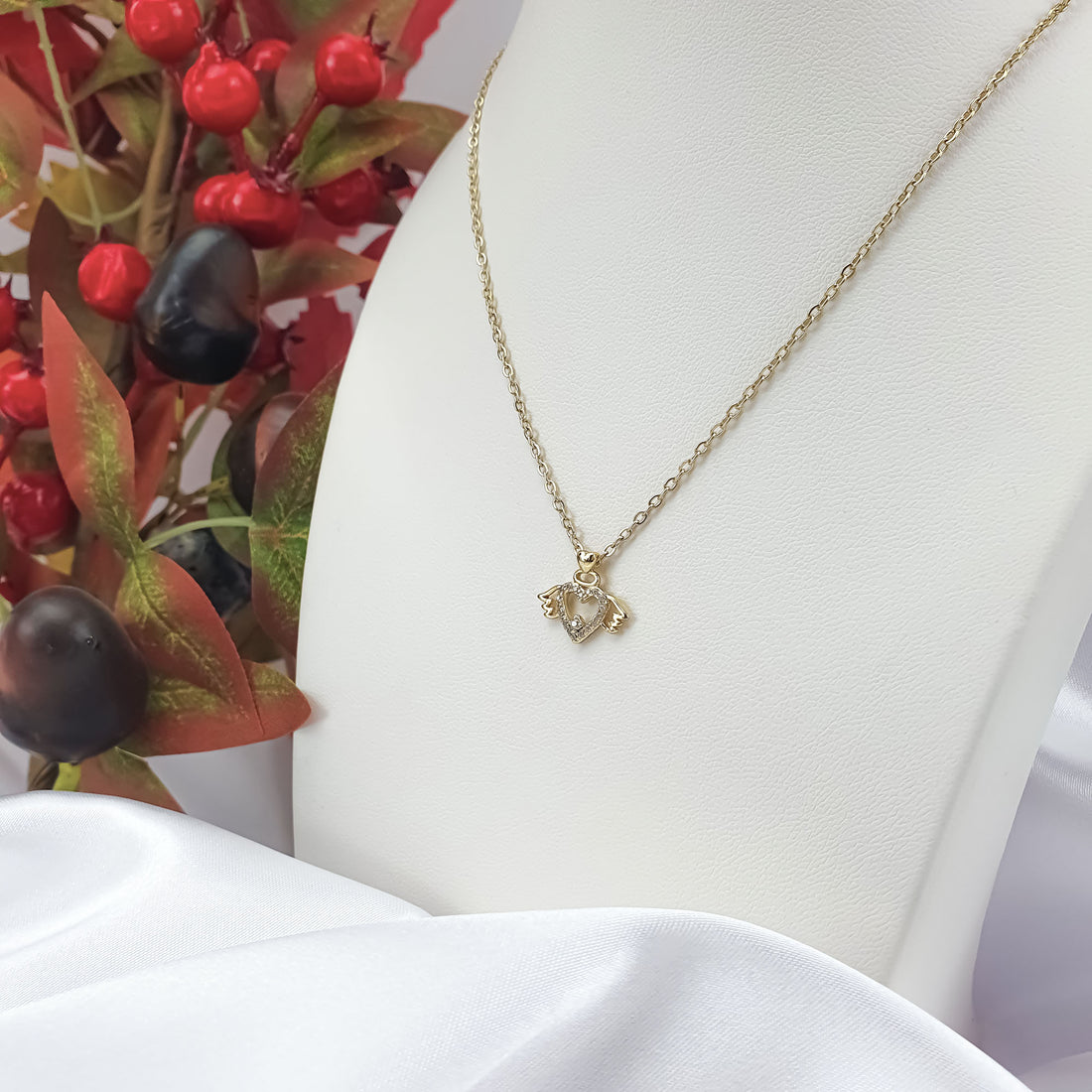 Winged heart necklace on a white display bust with an adjustable gold-plated chain