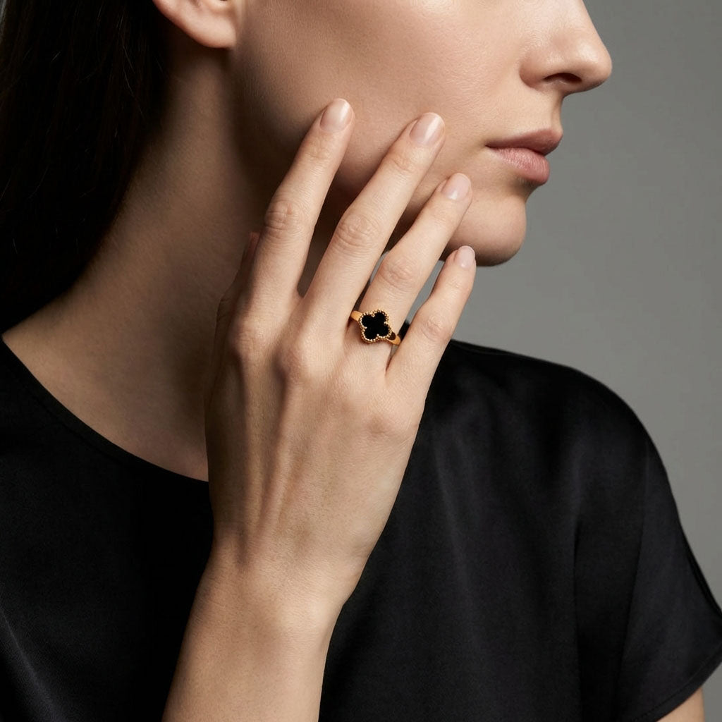 Gold-plated clover ring in black enamel on a model's finger near her face