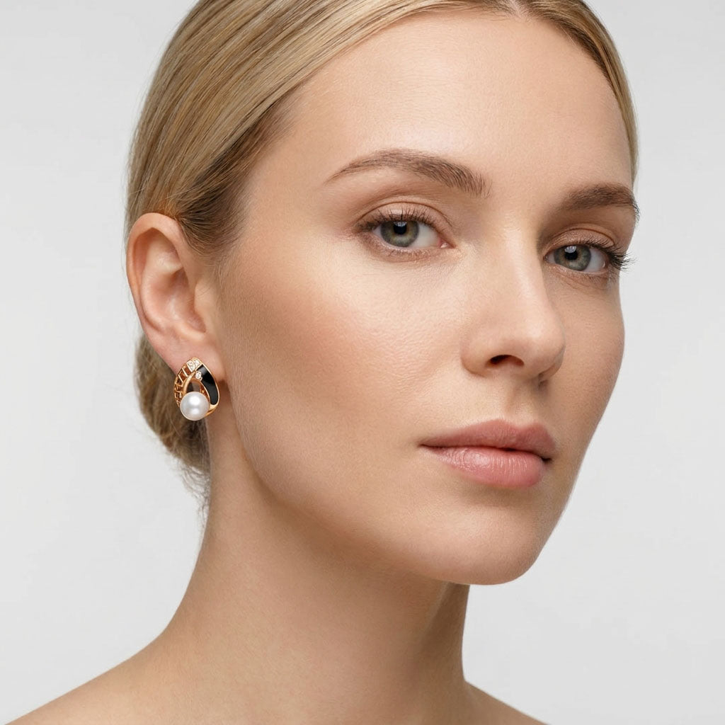 Model wearing a gold-plated pearl earring with black enamel and openwork pattern