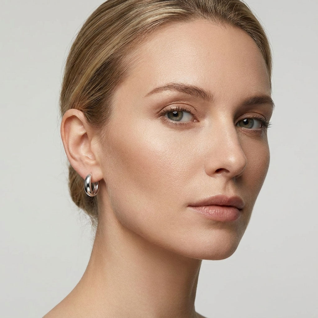 Model wearing small silver-tone hoop earrings in a bright portrait