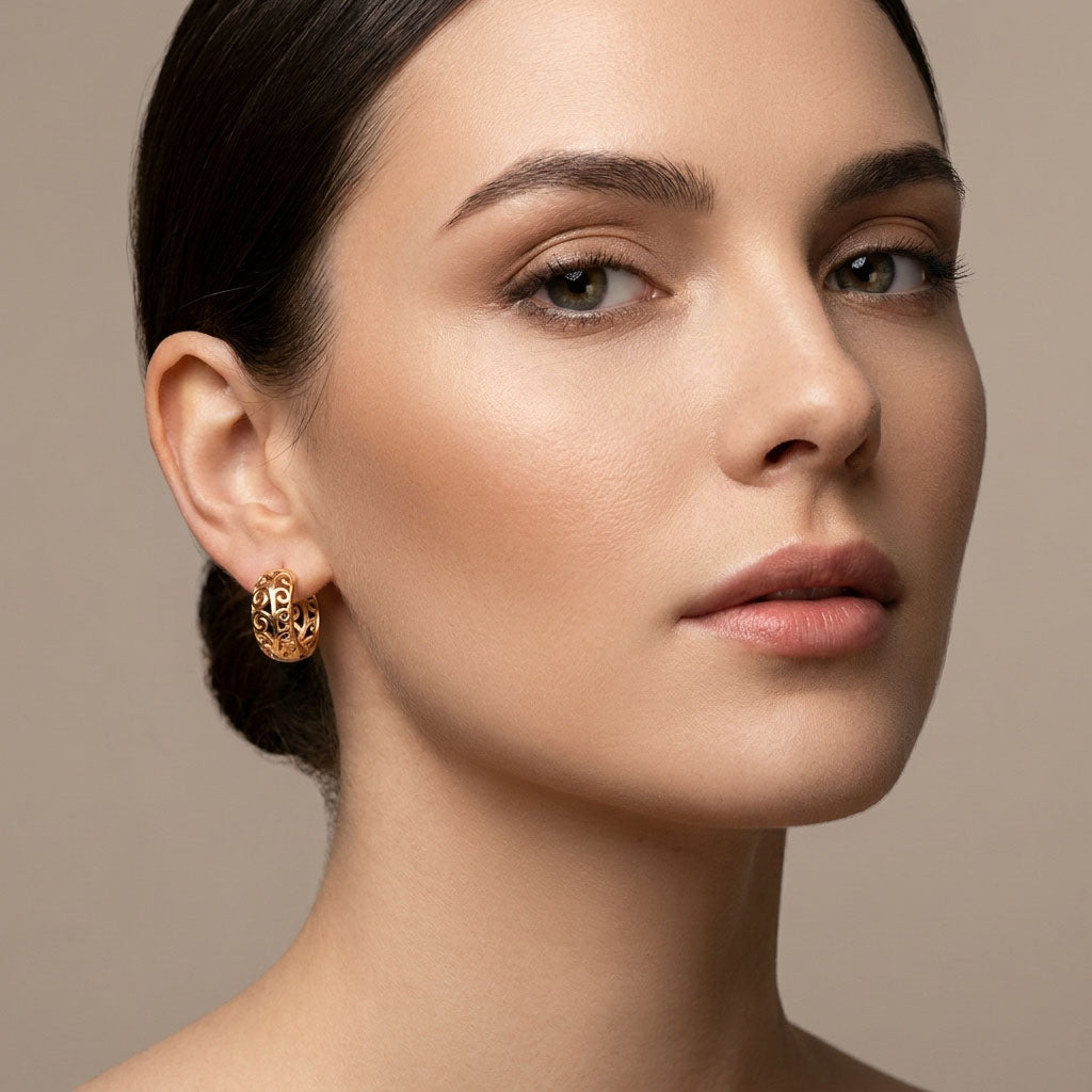 Model wearing gold-plated hoop earrings, pierced pattern glowing in warm light