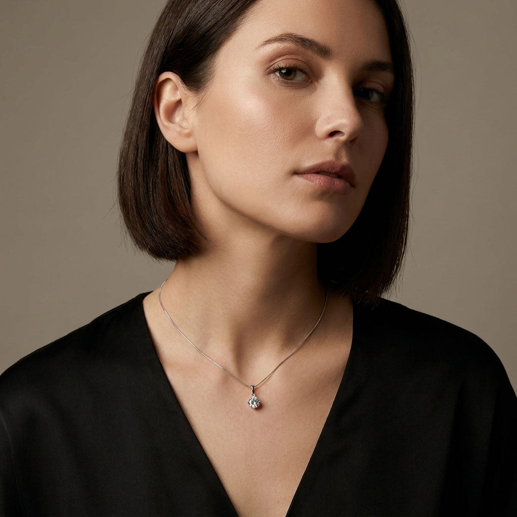 Model wearing a cubic zirconia pendant on a fine chain, black blouse