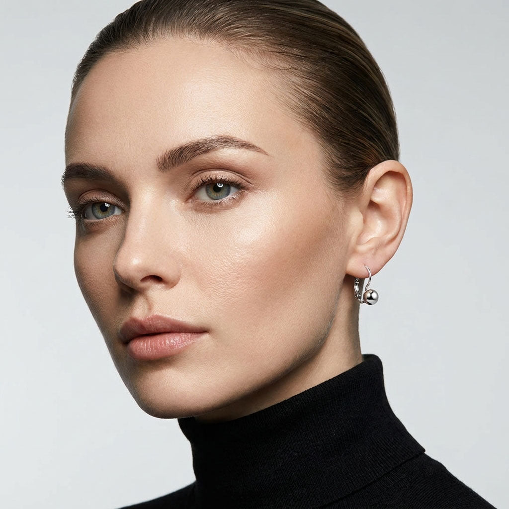 Silver-tone ball earring on a model's ear, black polo neck jumper