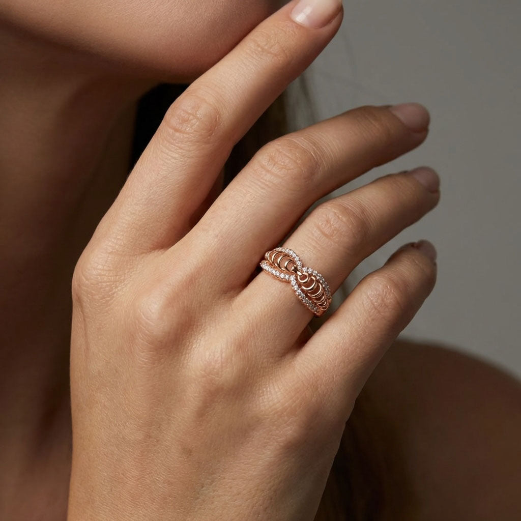 Wide gold-tone ring with a twisted cubic zirconia pattern on a model's finger