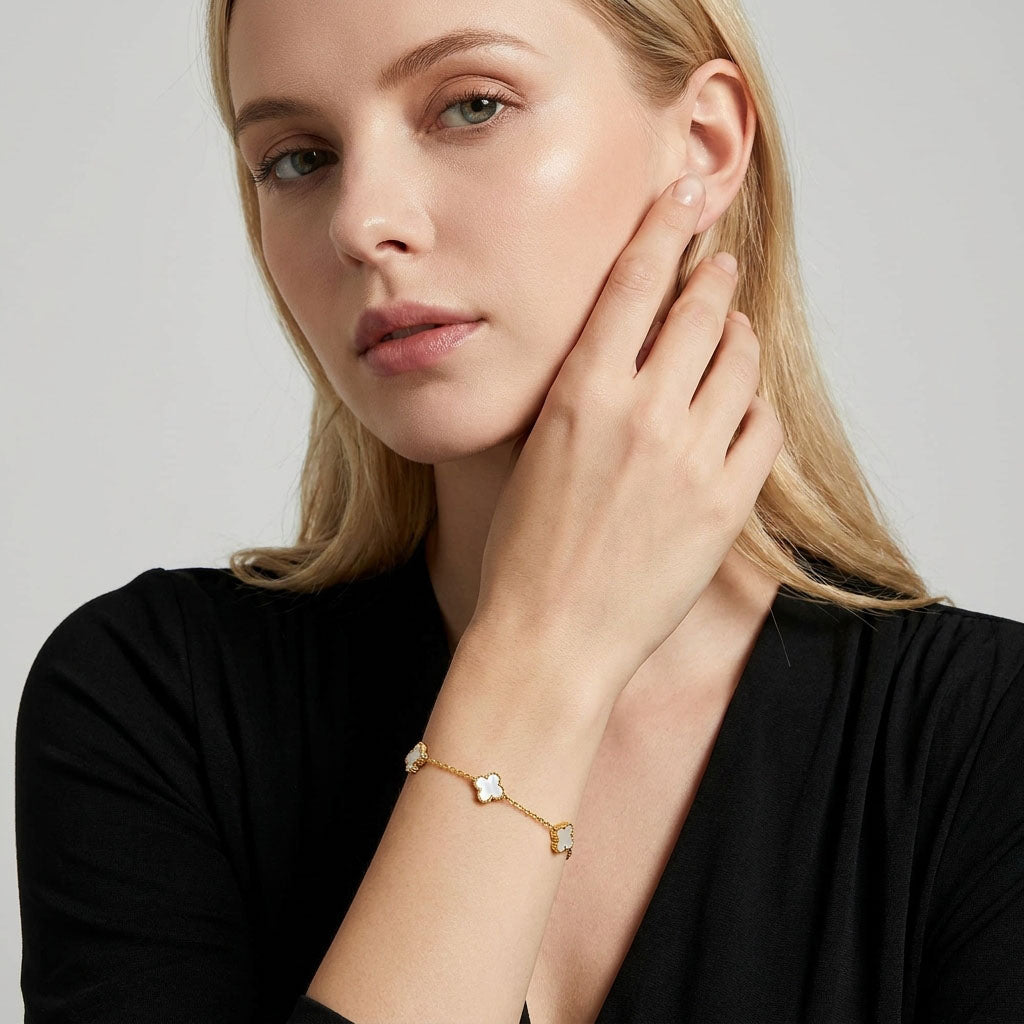 Woman in a black blouse wearing a gold-plated white clover bracelet