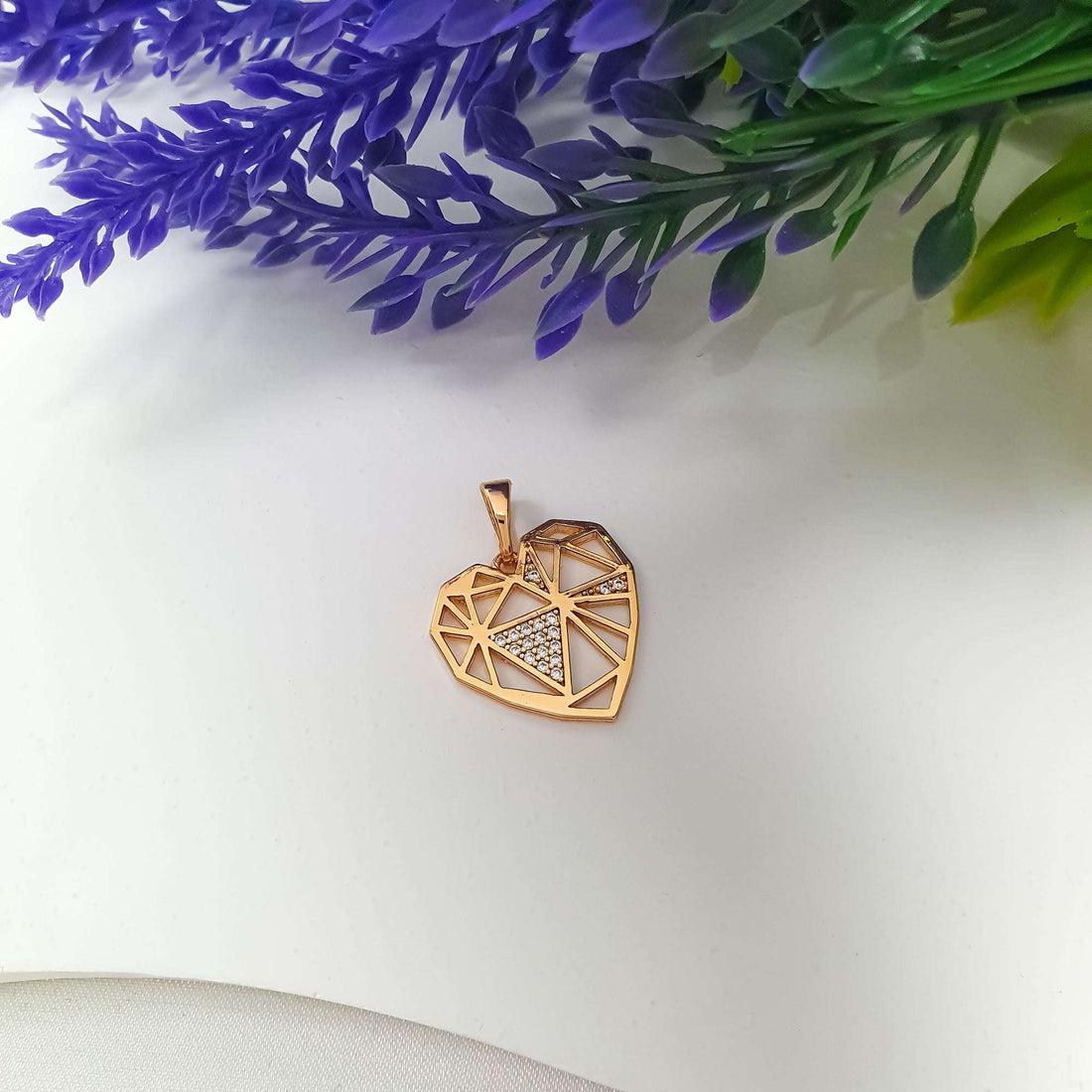 Openwork heart pendant at an angle, gold-tone lines and sparkling white stones
