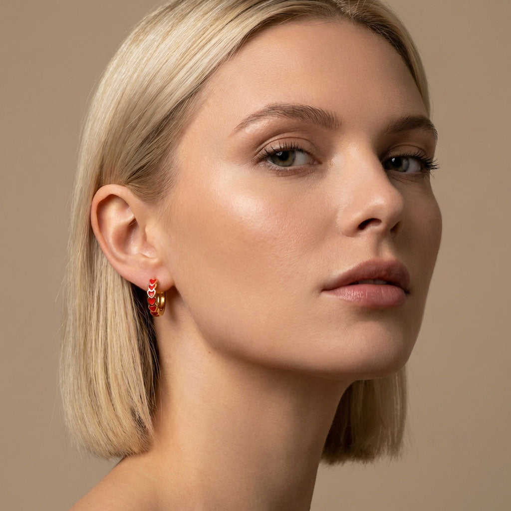 Fair-haired model wearing a gold-tone hoop with red enamel hearts