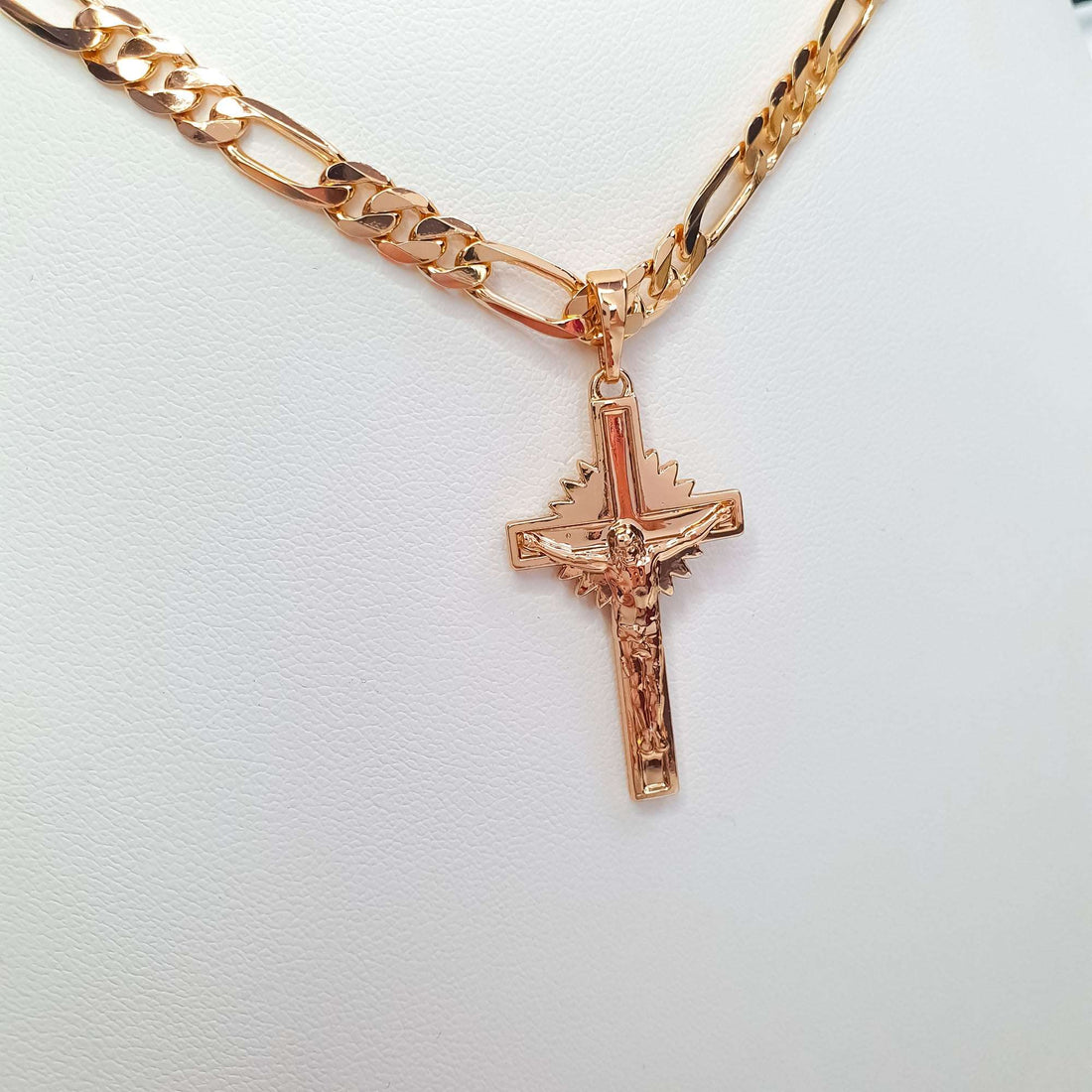 Close-up of the gold-tone crucifix on a chunky Figaro chain