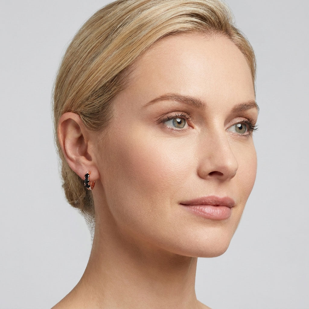 Model wearing small hinged hoops with black cubic zirconia sparkling at the front