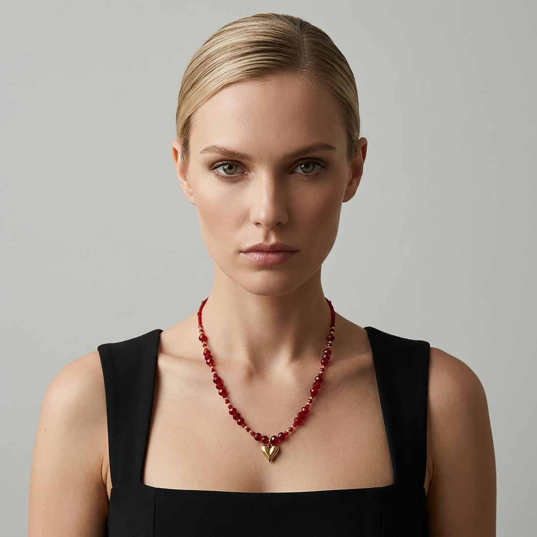 Model in a black dress wearing the red crystal necklace with a heart pendant