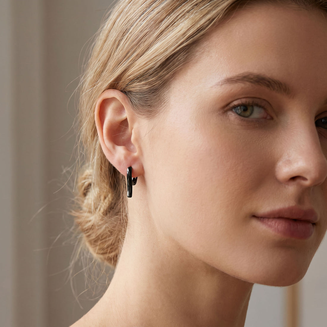 Black hoop earring with a bar worn on the earlobe