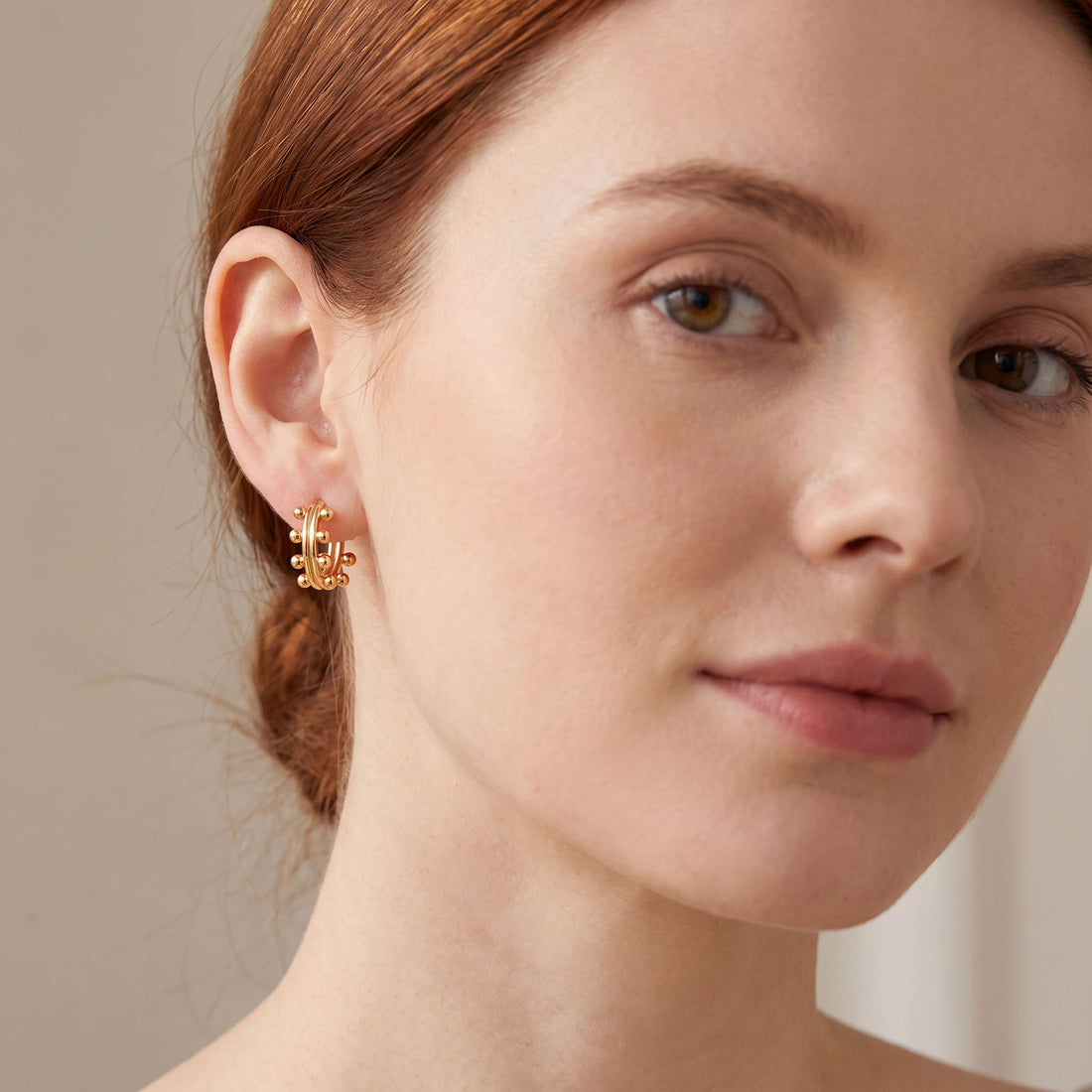 Gold-tone ball-studded hoop worn on the ear