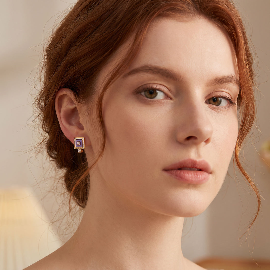 Gold-tone square earring with purple ceramic worn on the ear