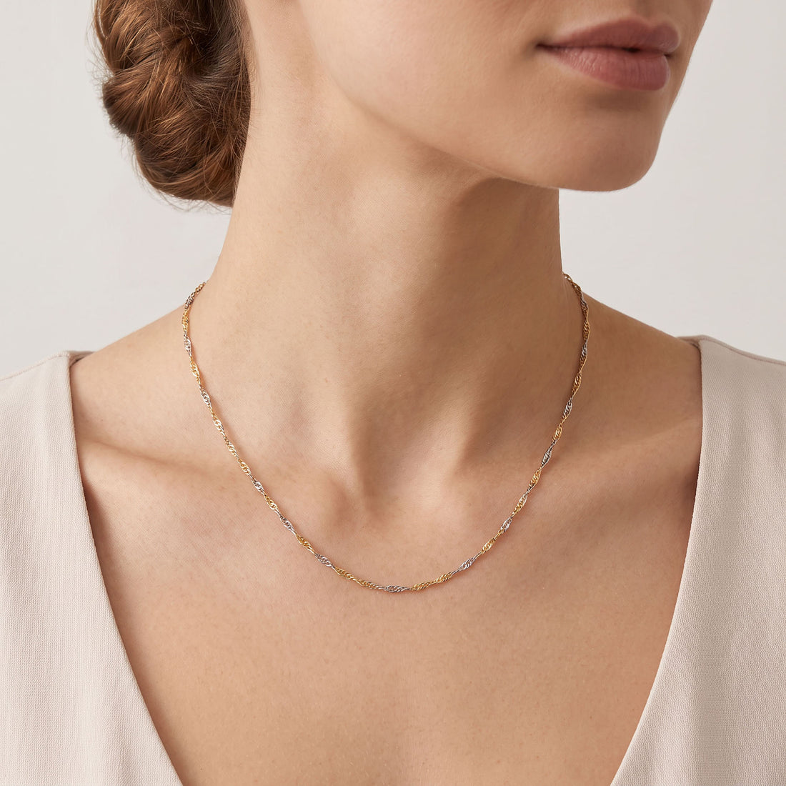 Two-tone Singapore chain in gold and silver tone worn on the neck