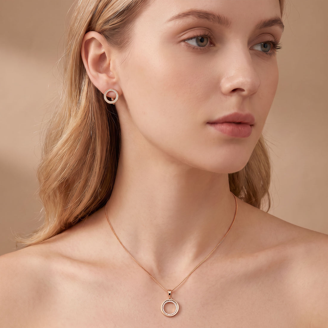 Gold-tone circle earring on the ear and pendant necklace worn on the neck