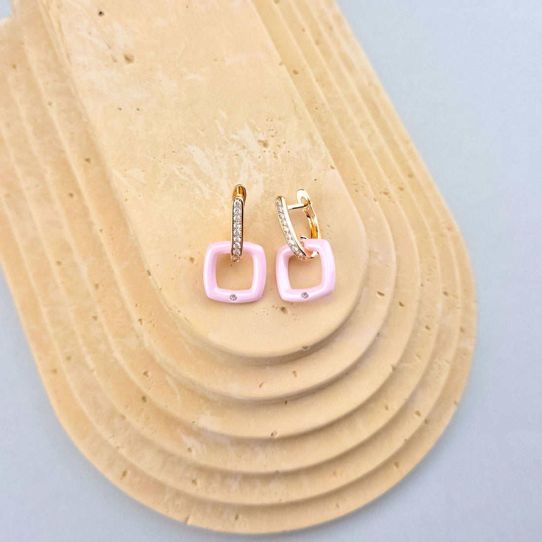 Gold-plated earrings with pink ceramic squares and cubic zirconia on a pale stone
