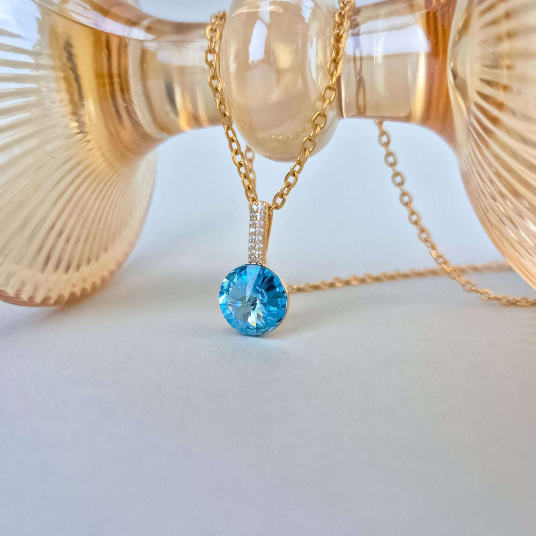 Close-up of the blue crystal pendant beside an amber glass vase