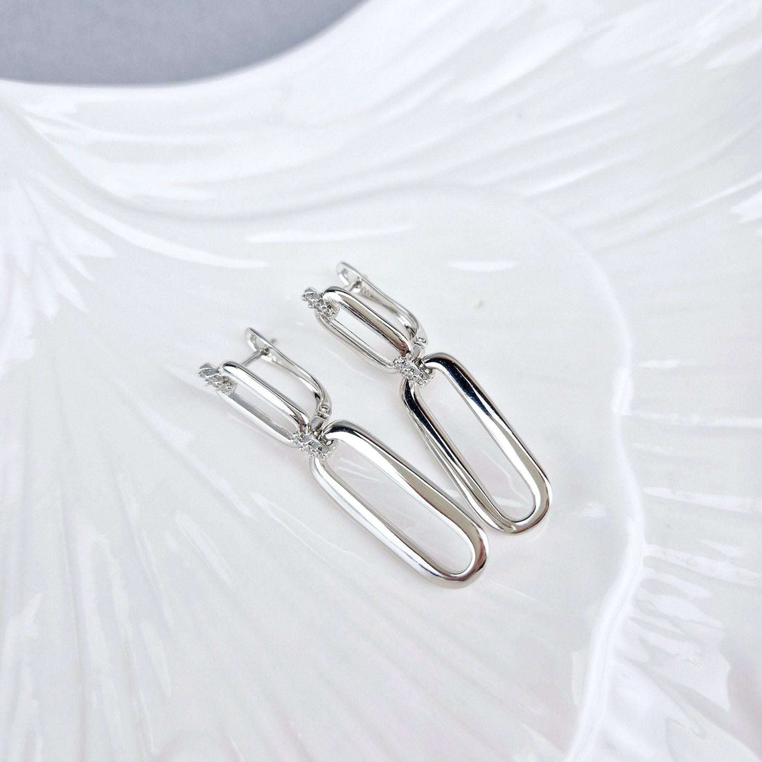 Long silver-tone link earrings at an angle, leverback and cubic zirconia visible