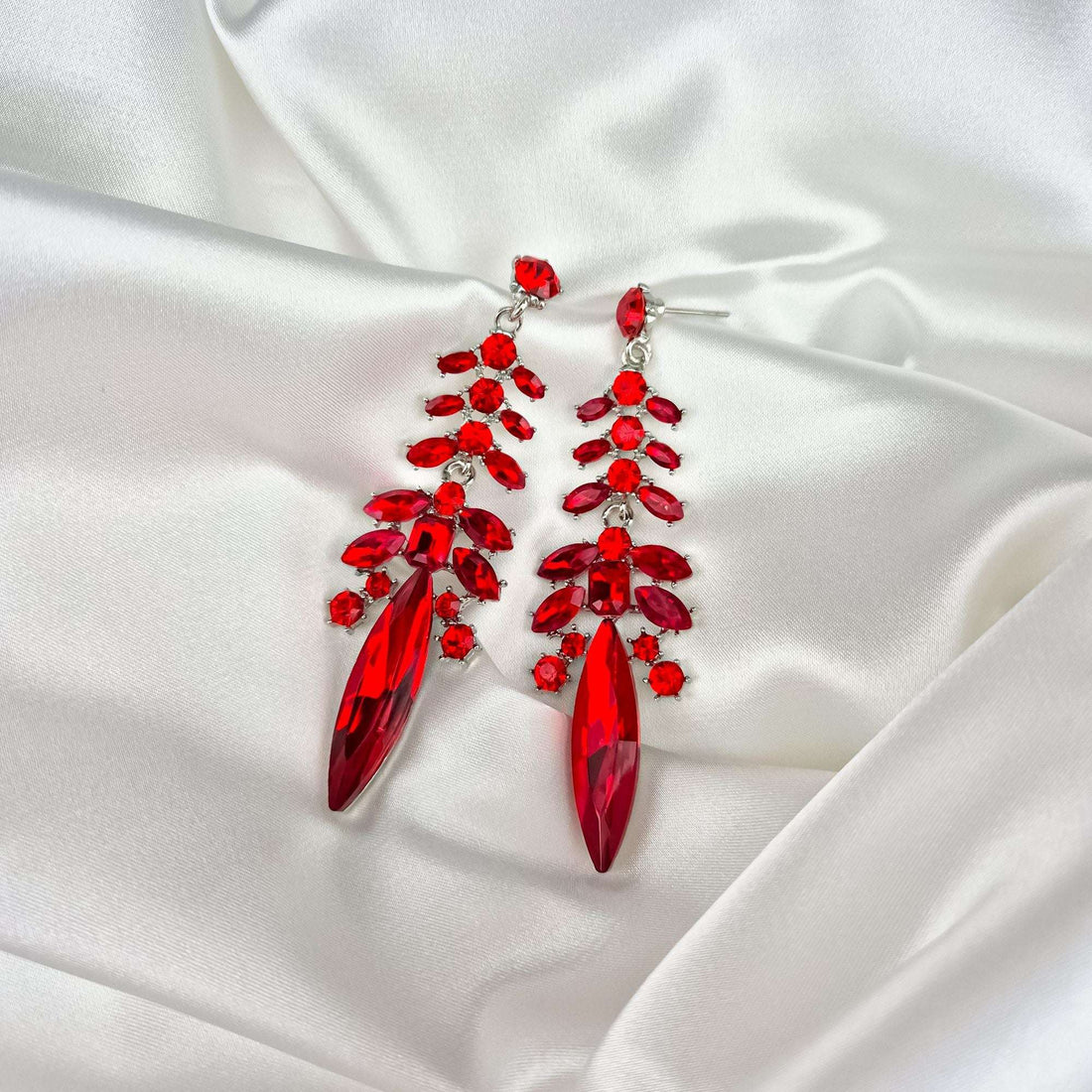 Red crystal earrings on white satin with the push-back post visible