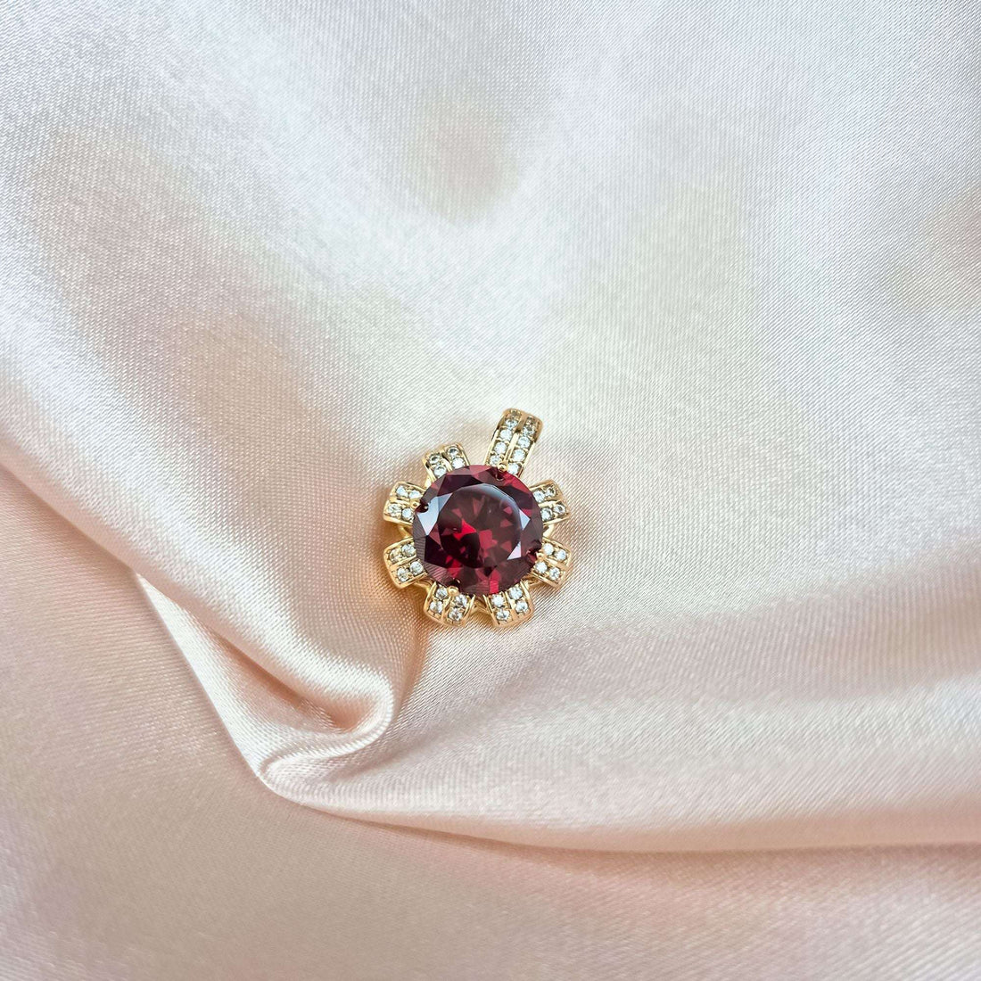 Gold-tone red crystal pendant with sparkling cubic zirconia on cream silk